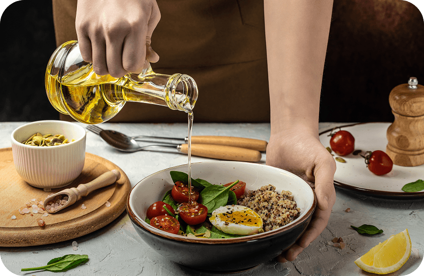 Pouring pure oil over a fresh salad bowl